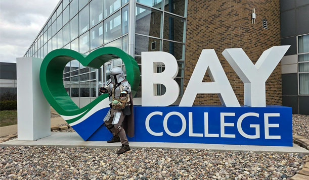 Boba Fett standing in front of the I Love Bay College sign