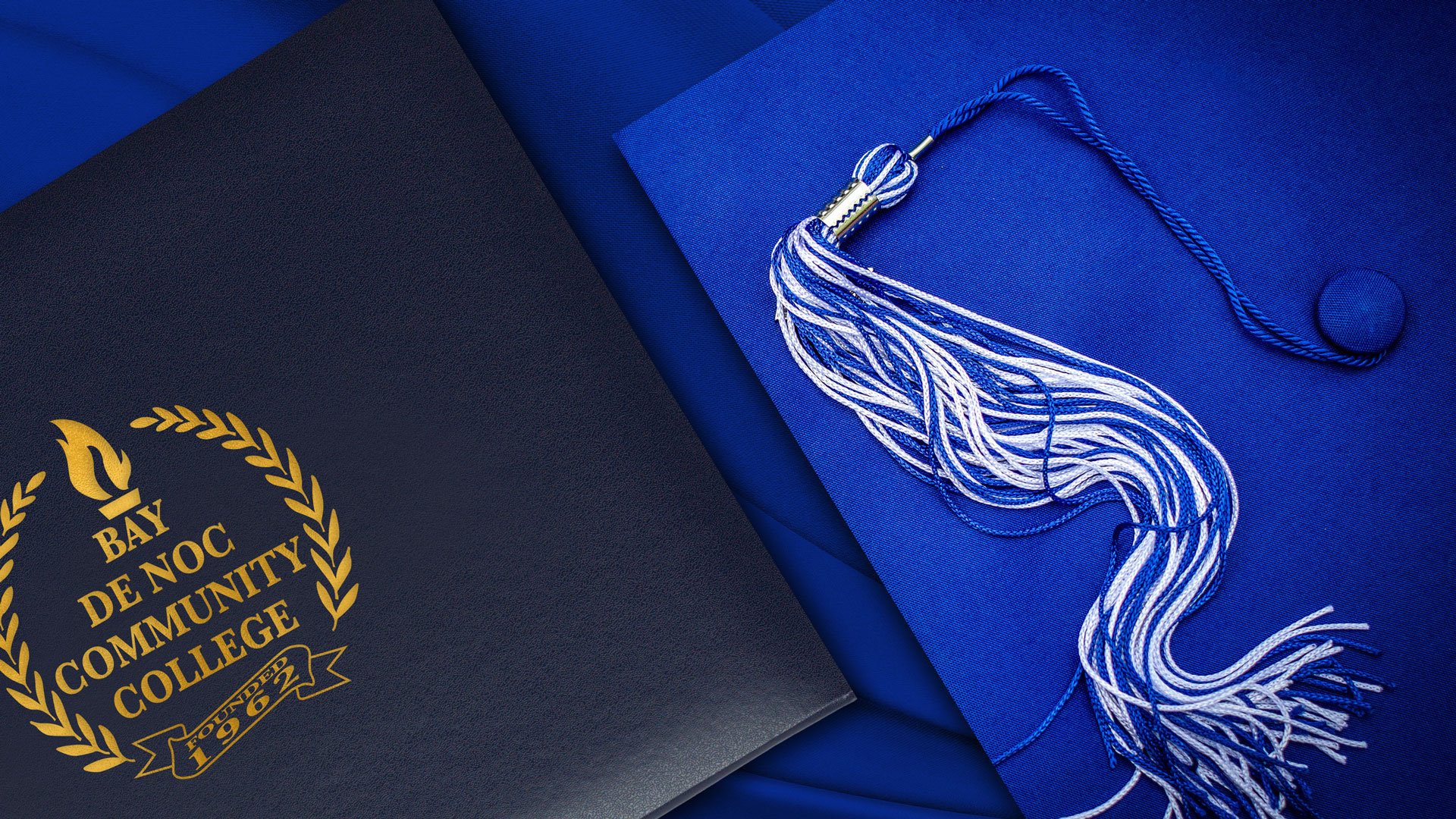 Navy blue Bay College diploma or certificate padded leatherette folder with the College name in gold beside royal blue grad cap with white and blue tassel.