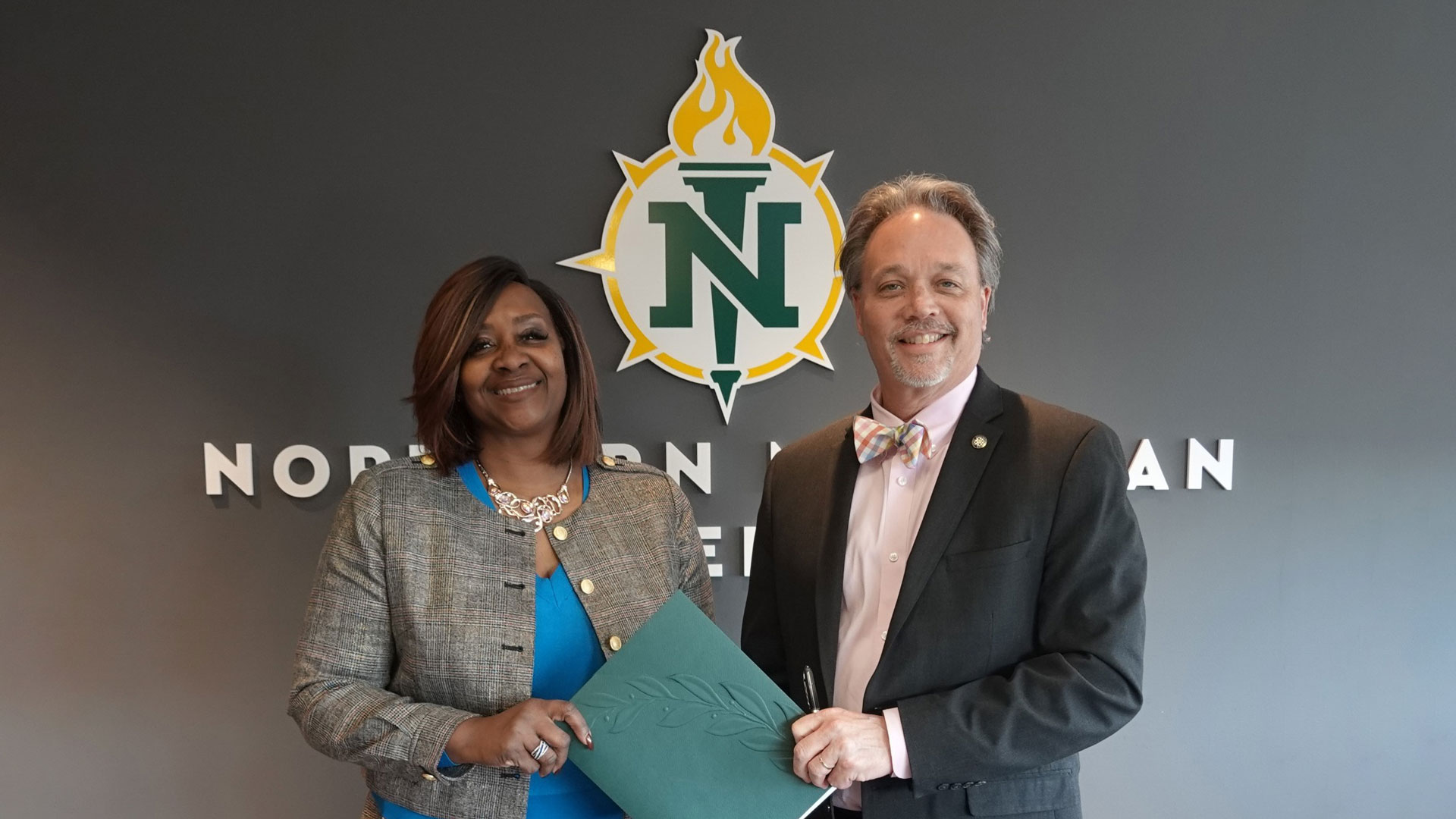 Bay College President Dr. Nerita Hughes and NMU President Chris Olsen stand side-by-side holding the transfer pathway agreement between them.