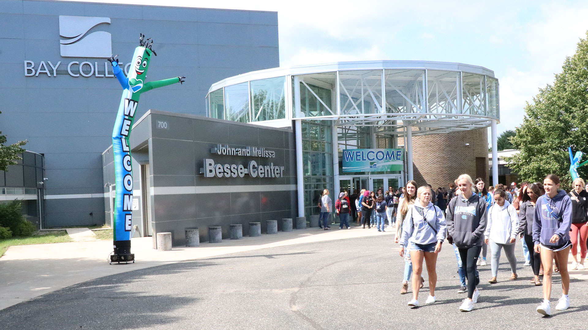 Bay College students exiting the Besse Center on the Escanaba Campus with welcome signs and windsocks around them.