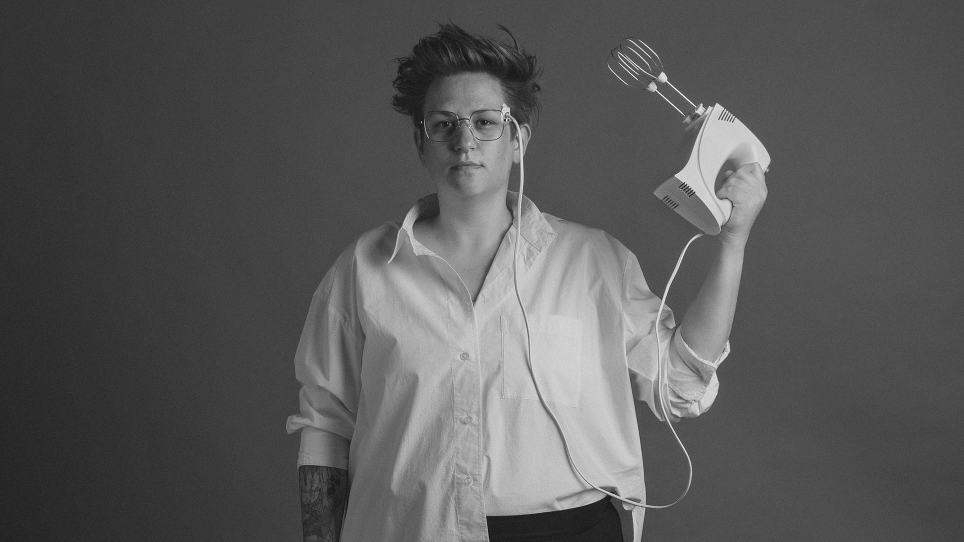 Electroacoustic composer and sound artist Ina Thomann holding an electric blender with a cord plugged into her eyeglasses.