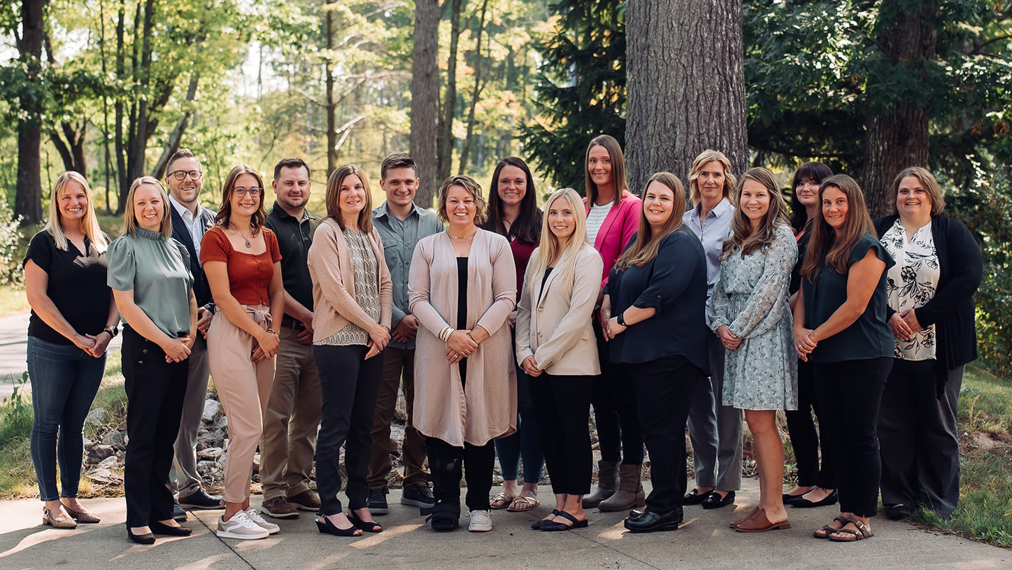 Bay College Leadership Academy participants gathered outdoors beneath the trees on the Iron Mountain campus at the completion of the 2024-2025 program.