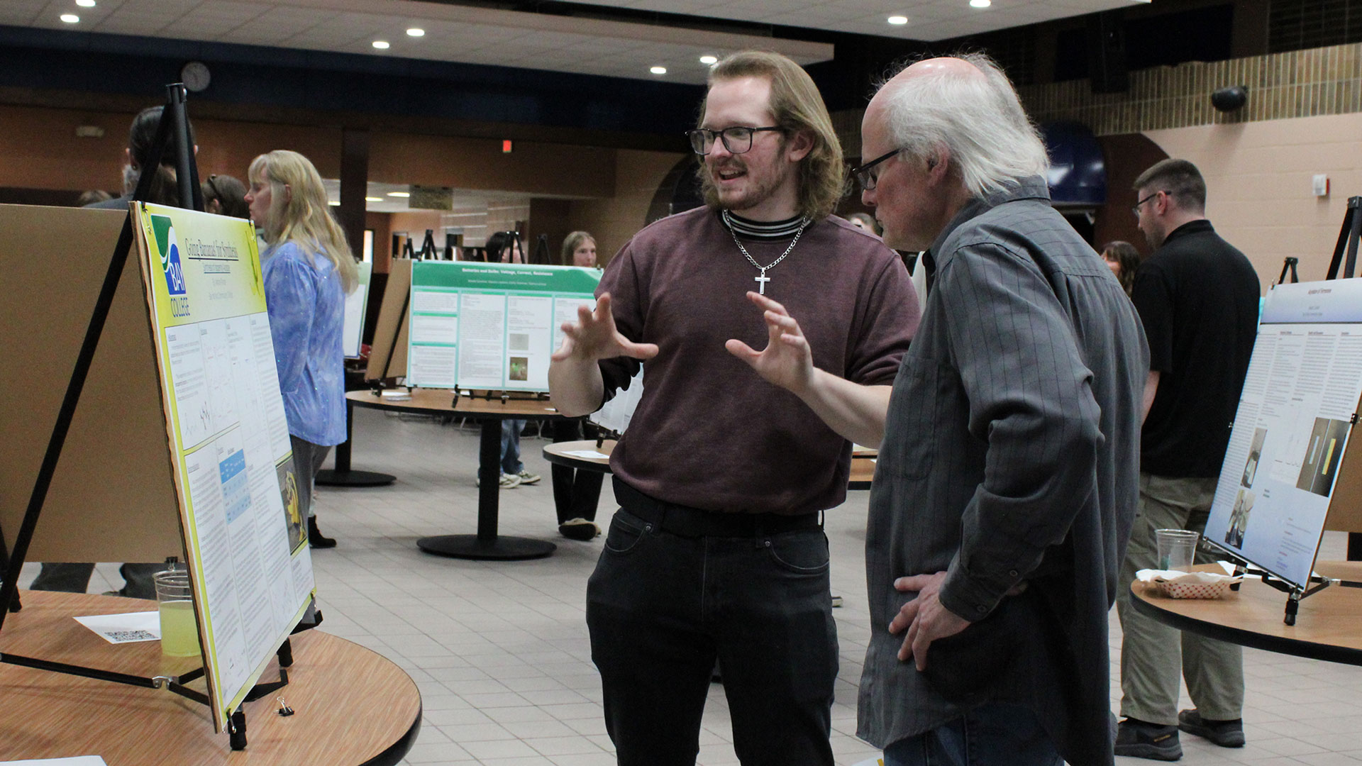Bay College student Adrian Rhode discusses his poster on the synthesis of isopentyl acetate with Dr. Matthew Krynicki.