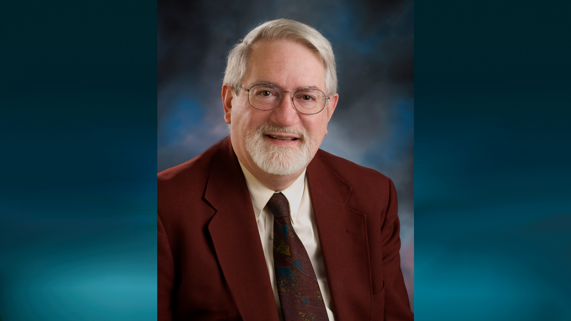 Bay College Trustee Emeritus Thomas L. Butch in glasses wearing a dark brown suit and tie with a cream colored dress shirt.